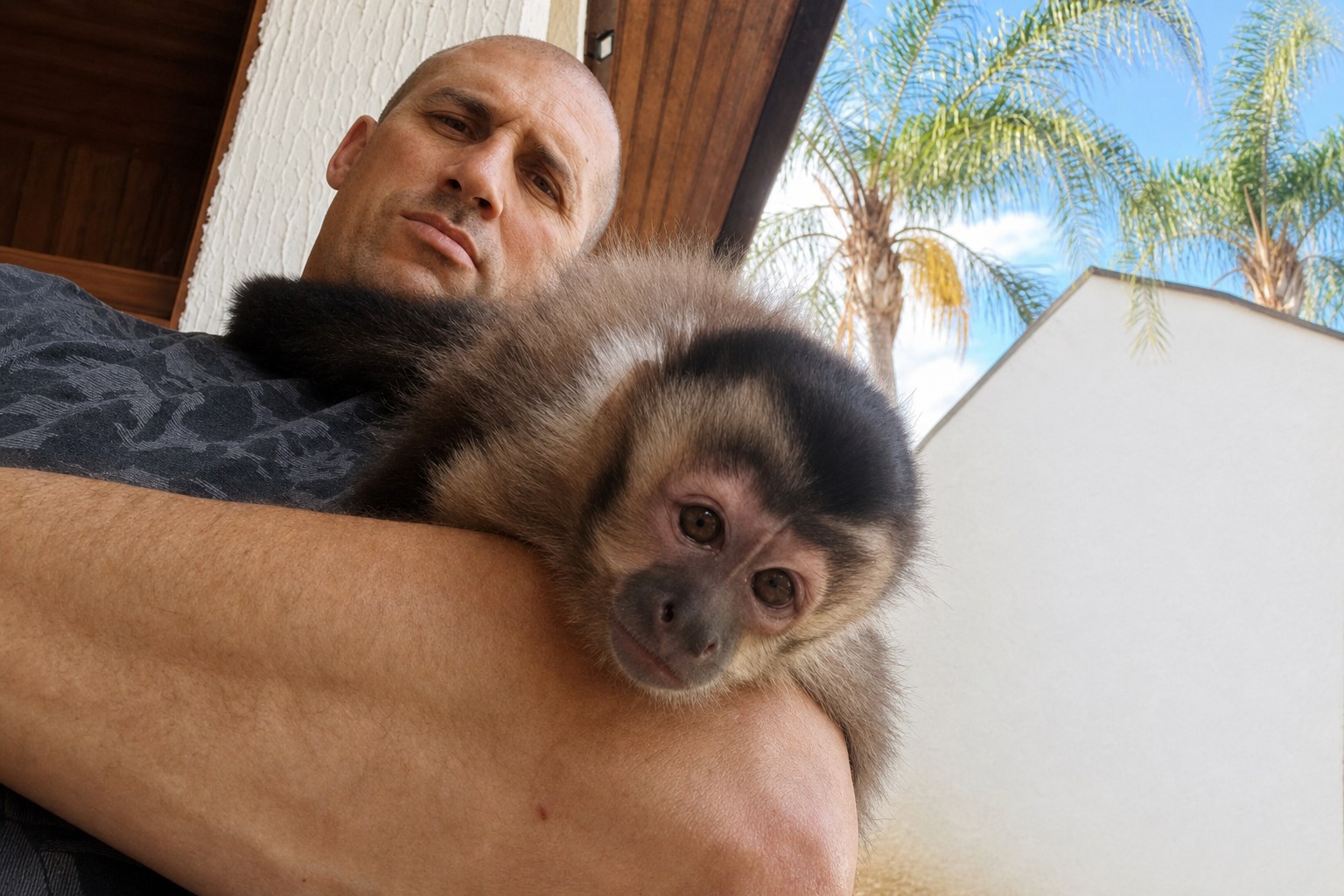 Julio Costa segurando um macaquinho em uma área externa.